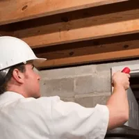 Termite inspection technician checking a basement wall and framing for termite activity in {city}, {state}